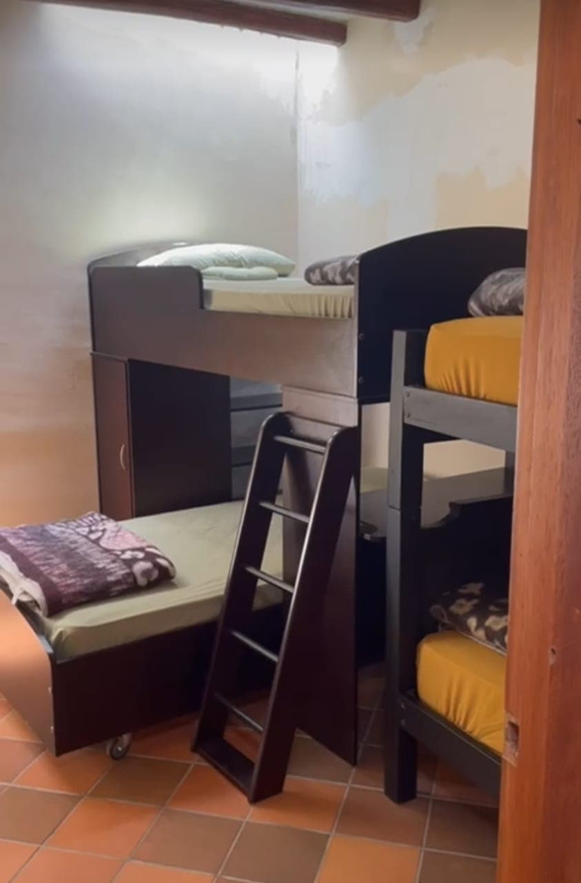 Participant bedroom at Teos, multiple bunk beds with warm yellow and earth-tone bedding, terracotta tile floor