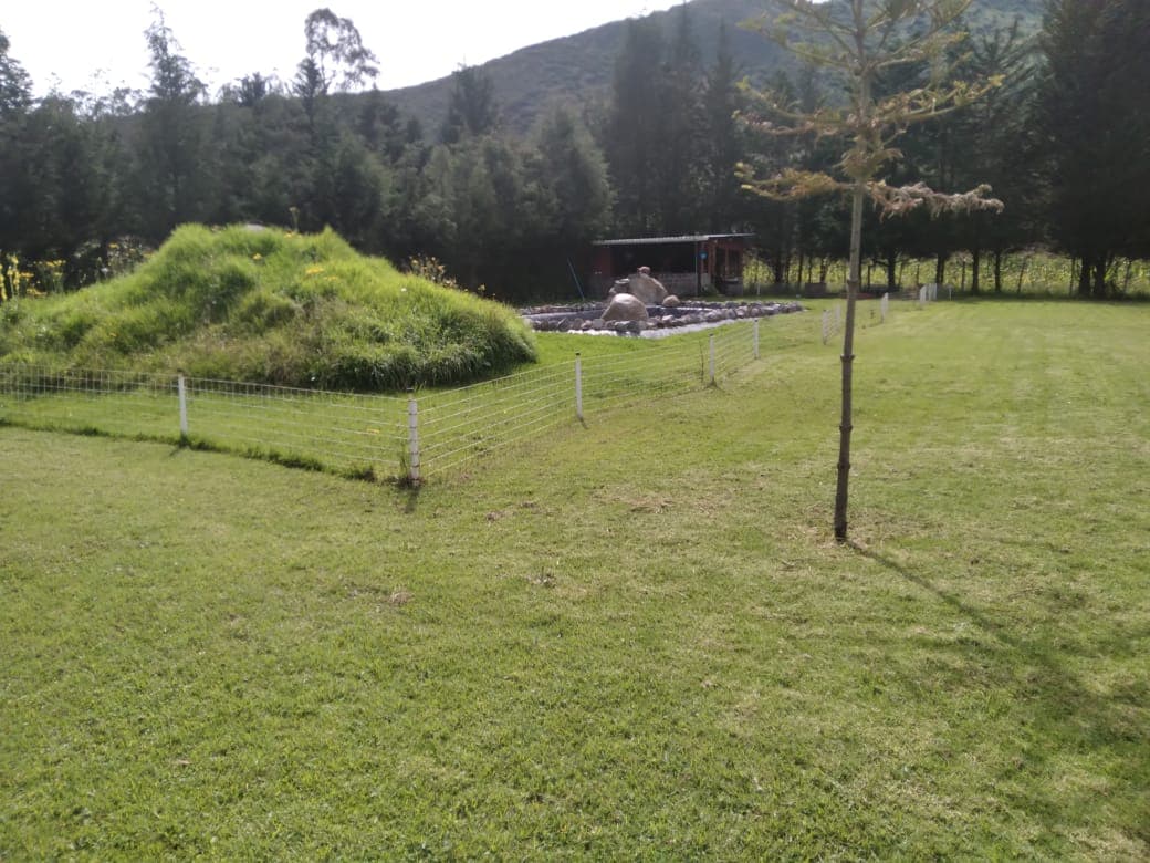Earth-mound temazcal sweat lodge built into the hillside at Calacalí, mountains rising behind