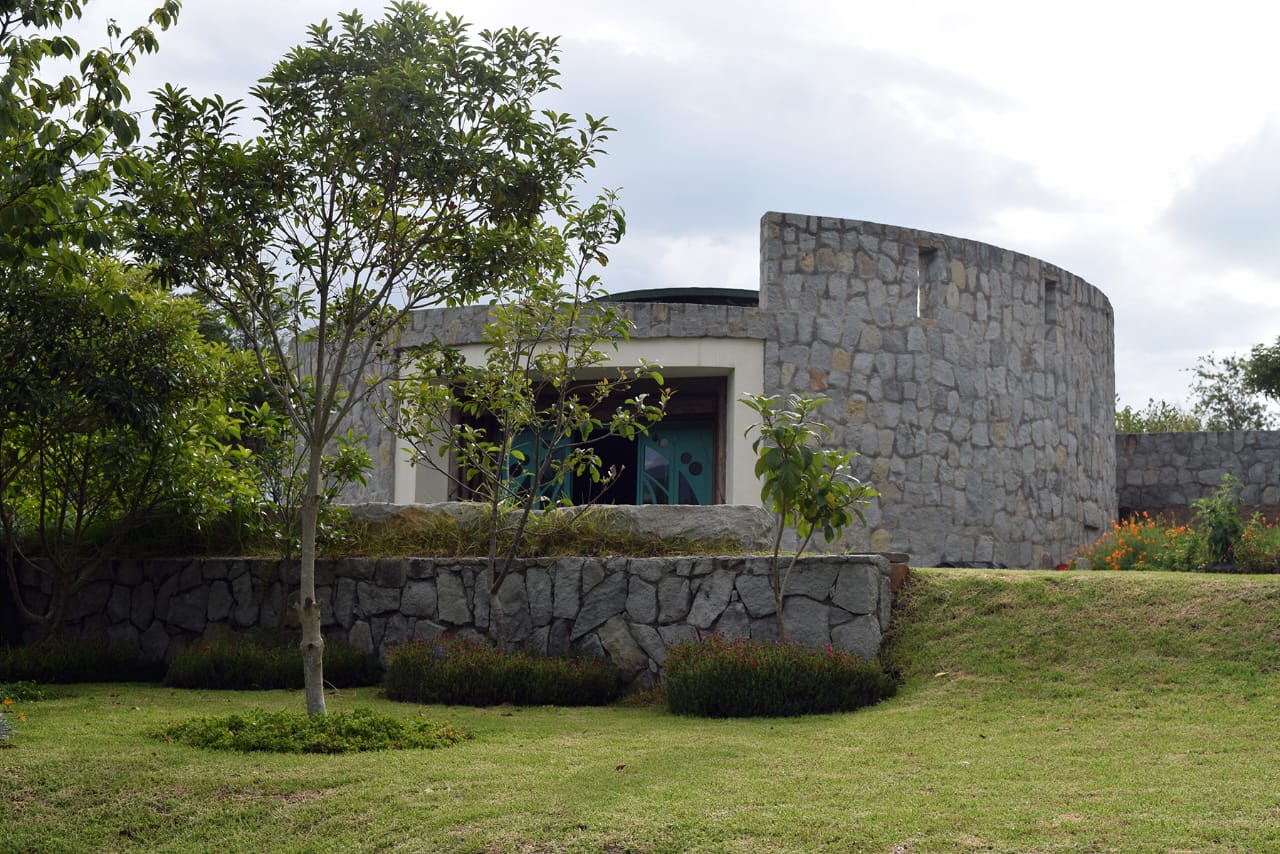 Stone maloka exterior at Teos Center, surrounded by gardens