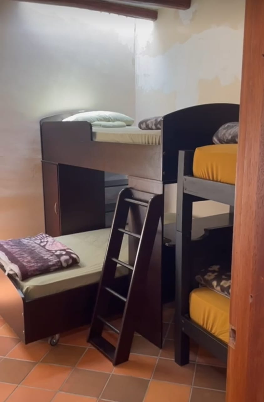 Participant bedroom at Teos — multiple bunk beds with warm yellow and earth-tone bedding, terracotta tile floor