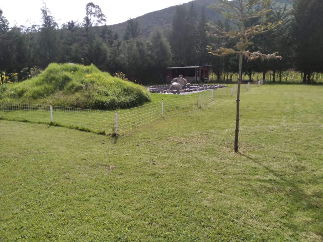 Earth-mound temazcal sweat lodge built into the hillside at Calacalí, mountains rising behind